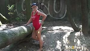A sports-loving blonde lifts up one leg while enjoying a pee standing on the ground
